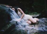Young woman lying on small waterfall